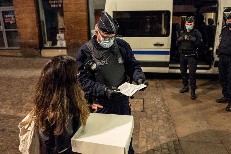 Police speak with a pedestrian as they patrol in the streets of Toulouse at the start of a curfew. AFP