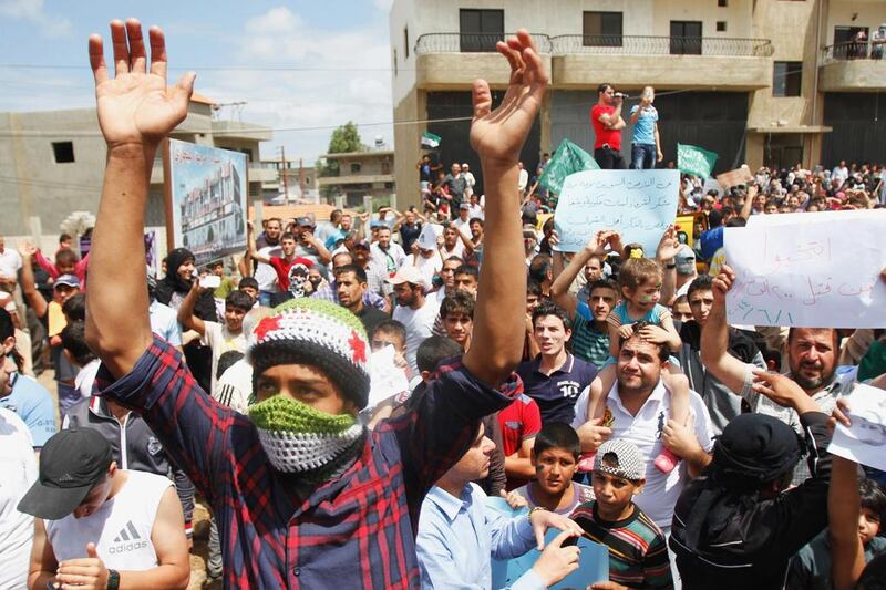 A Syrian refugee wearing a scarf in the colours of the Free Syrian Army flag during a protest in Tripoli on Sunday against Syria's presidential election. Omar Ibrahim / AP