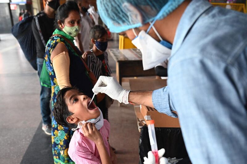 A health worker takes a swab sample from a child for a Covid-19 test at a railway station in New Delhi. AFP