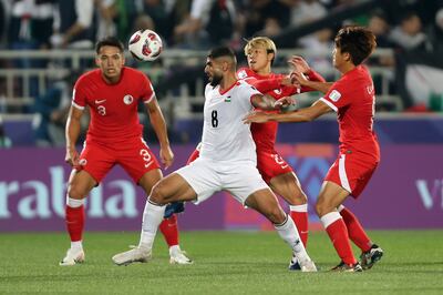 Palestine's Alaeddin Hasan, centre, fights for the ball against Hong Kong opponents during an Asian Cup Group C match in Doha, Qatar. AP Photo