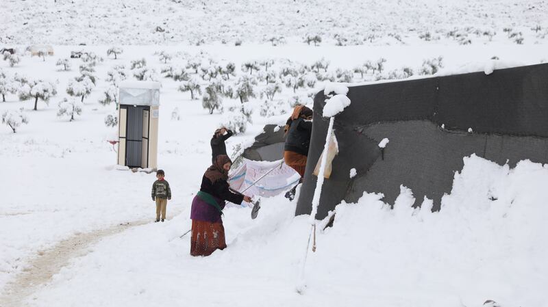 A woman removes snow from her tent