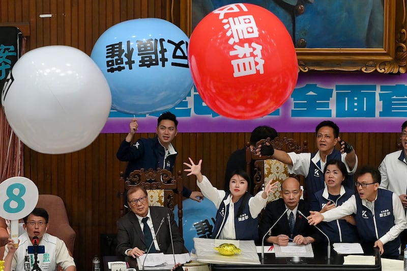 Legislators from the main opposition Kuomintang party stop balloons protesting 'black box operations' from hitting Parliament Speaker Han Kuo-yu in Taipei. AFP