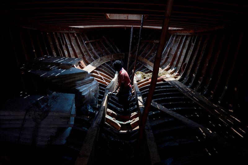 A carpenter works to repair a fishing boat on the eve of May Day in Chennai, India. AFP