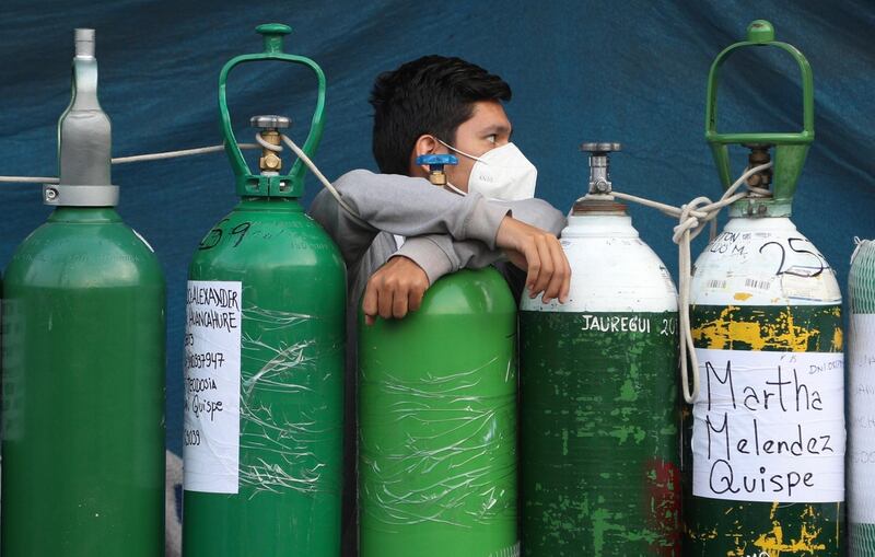 A youth rests on his empty oxygen cylinder waiting for a refill shop to open in the San Juan de Lurigancho neighborhood of Lima, Peru. AP Photo