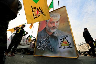 Kataib Hezbollah Iraqi militants hold a picture of the Iranian Maj Gen Qassem Suleimani at a rally after his death from a US air strike in 2020. Reuters