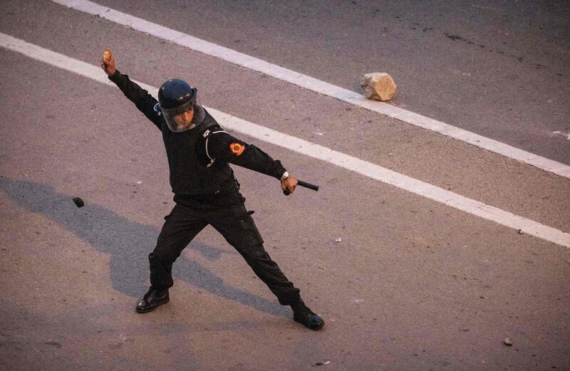 A Moroccan riot police officer throws back a rock at migrants during the clashes in Fnideq. AFP