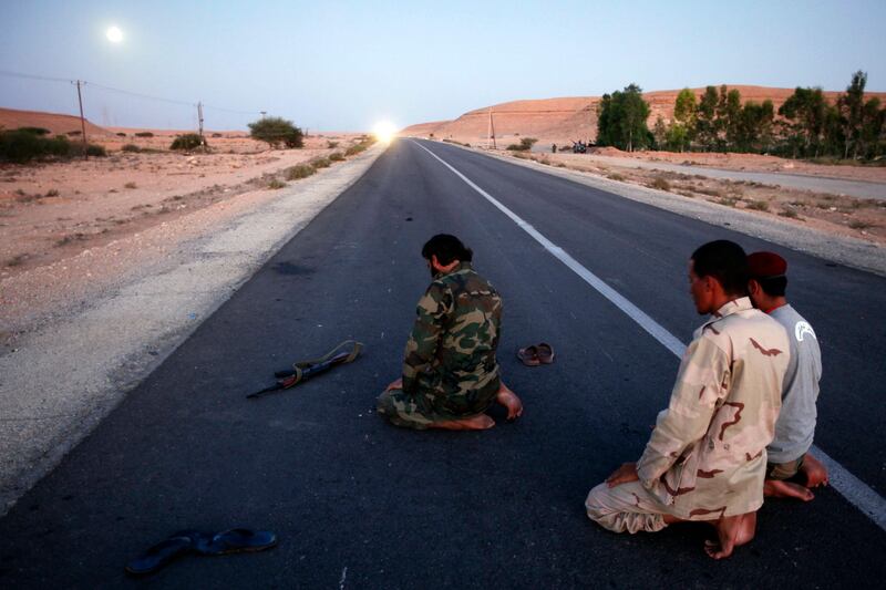 Anti-Gaddafi fighters pray near the north of the besieged city of Bani Walid September 12, 2011. Forces of Libya's new rulers met "ferocious" street-by-street resistance during an assault on one of the last bastions loyal to Muammar Gaddafi, but were edging towards the ousted ruler's birthplace of Sirte. The National Transitional Council's forces, which toppled Gaddafi last month, said they were facing about 1,000 loyalist fighters in the Gaddafi stronghold of Bani Walid, far more than the 100 to 150 men they had estimated earlier, while discipline had slipped in their own ranks. Residents fleeing Bani Walid reported intense street fighting, while NATO warplanes could be heard overhead. REUTERS/Youssef Boudlal (LIBYA - Tags: MILITARY CONFLICT RELIGION TPX IMAGES OF THE DAY) *** Local Caption ***  YB123_LIBYA-_0912_11.JPG