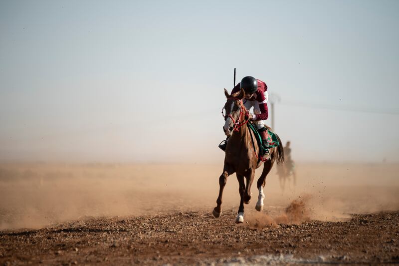 A horse and rider at full tilt on the desert track
