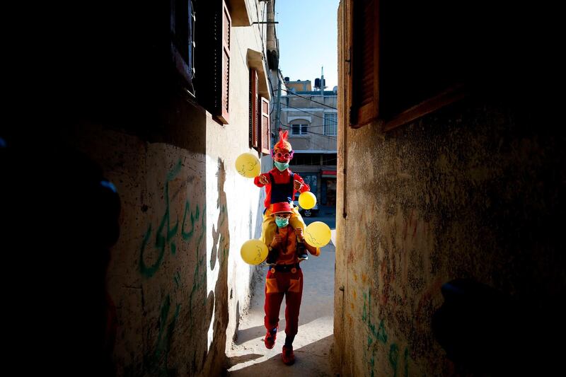 Clowns, wearing surgical masks due to the COVID-19 coronavirus pandemic, walk with balloons in al-Nusairat refugee camp in the central Gaza Strip as they celebrate with children the start of Ramadan.  AFP
