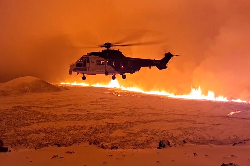 A coastguard helicopter flies close to near magma flowing down a hill on Iceland's Reykjanes Peninsula on Monday night. AP