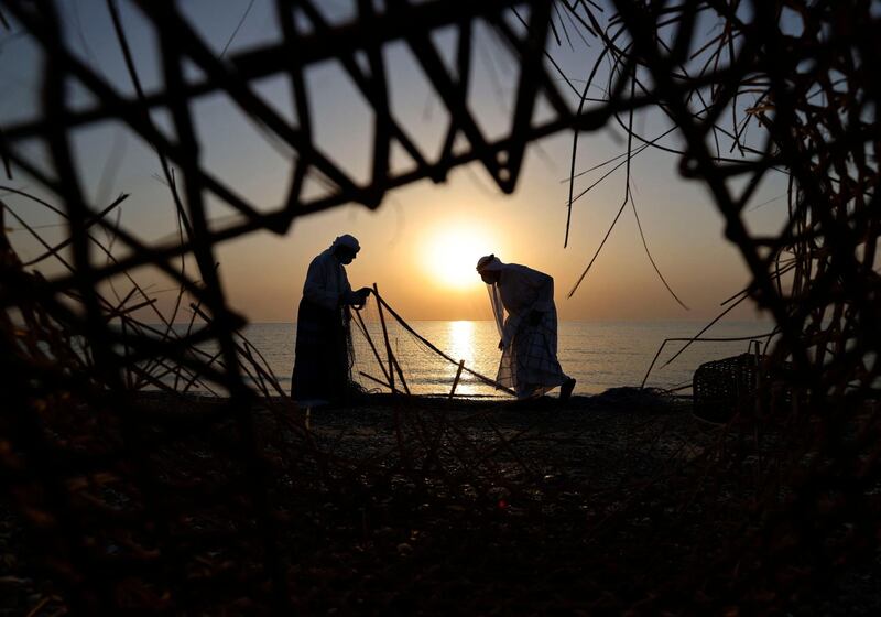 Emirati fishermen are silhouetted against a low sun as they sort their nets at Dalma island. AFP