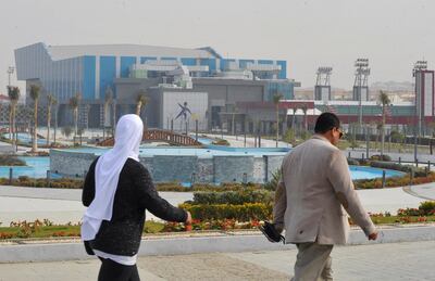 Egyptians walk in front of the main gate of New Capital Stadium that will host the IHF Handball World Championship in January 2021 in the New Administrative Capital (NAC), east of Cairo, amid concerns about the spread of the coronavirus disease (COVID-19), in Egypt December 28, 2020. Picture taken December 28, 2020. REUTERS/Shokry Hussien