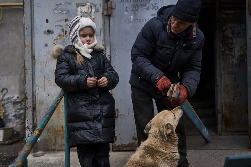 Sasha and her grandfather stand outside their home in Bakhmut. AP