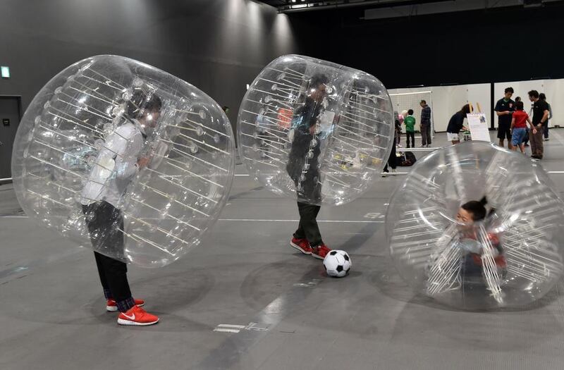 People, wearing plastic made bubble balls, enjoy a three-on-three game of bubble-soccer at the National Museum of Emerging Science and Innovation in Tokyo on November 1, 2014.  The museum offers vistors a chance to experience a Norwegian born new sport. AFP