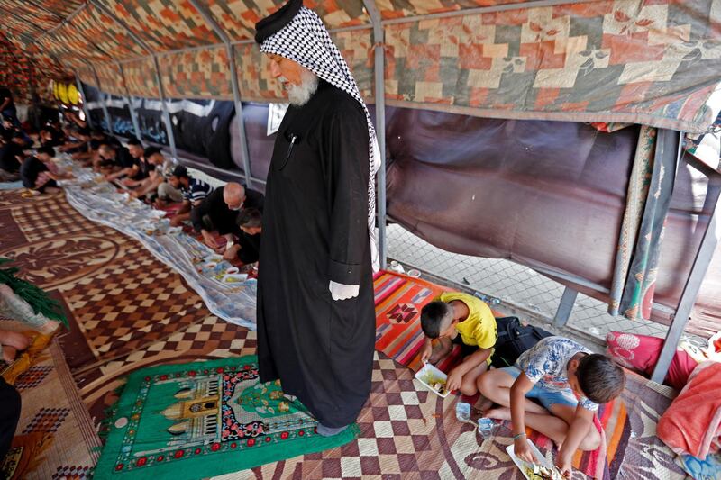 An Iraqi Shiite Muslim pilgrim, Mohammed Al Mohammedawi, prays and others eat at a tent set up by volunteers to provide a place for pilgrims to rest. Reuters
