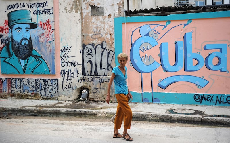 An elderly woman walks along a street next to street art in Havana. All photos by Yamil Lage / AFP Photo