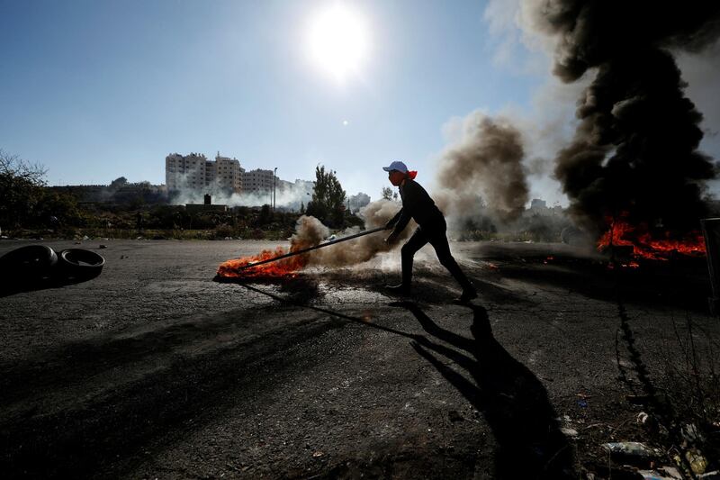 A Palestinian protester moves a burning tire during clashes. Mohamad Torokman / Reuters