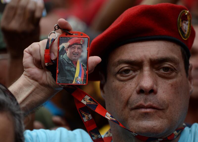 A man holds a picture of late Venezuelan president Hugo Chavez as he takes part in a rally in support of the economic measures taken by President Nicolas Maduro, in Caracas. AFP