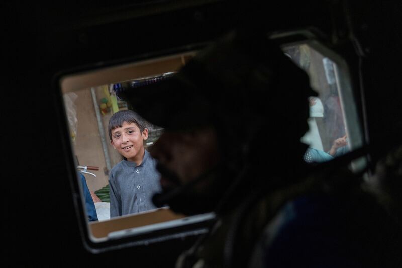 A boy watches as a convoy of Afghan Special Forces passes through a market during a combat mission against Taliban, in Kandahar province, Afghanistan, July 13, 2021.