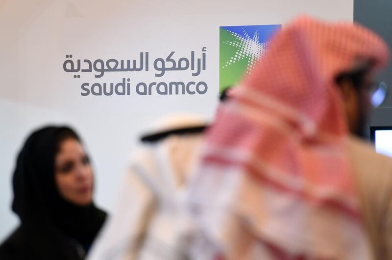 (FILES) In this file photo taken on January 25, 2016, Saudi and Foreign investors stand in front of the logo of Saudi state oil giant Aramco during the 10th Global Competitiveness Forum in the capital Riyadh. Saudi state-owned energy giant Aramco said on August 12 that its first half net income for 2019 had slipped to $46.9 billion, a first such disclosure for the secretive company ahead of its debut earnings call. "The company's net income was $46.9 billion for the first half (of) 2019, compared to $53.0 billion for the same period last year," the company said in a statement. The fall in income, owing to lower oil prices, comes amid renewed speculation the company was preparing for its much-delayed overseas stock listing. / AFP / Fayez Nureldine
