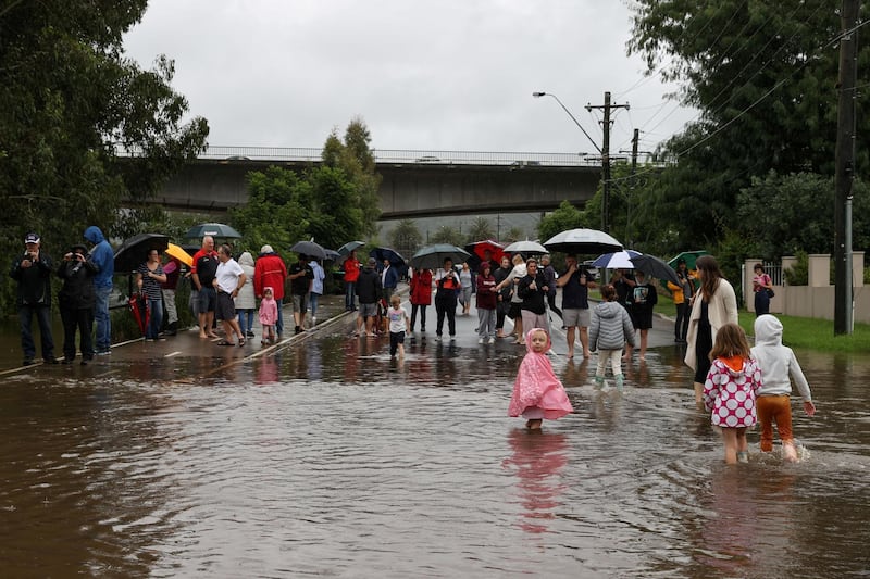 People gather on a flooded residential street, near the swollen Nepean River in Sydney, as Australia's New South Wales state experiences widespread flooding and severe weather. Reuters