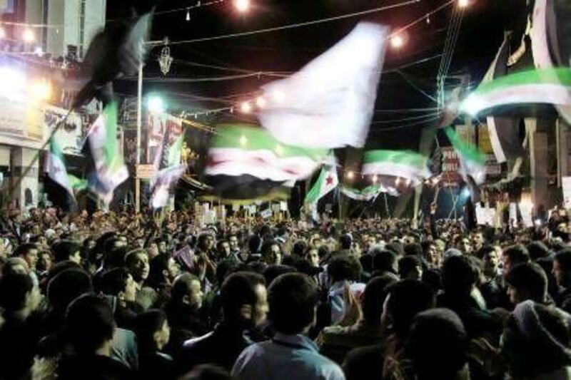 Syrians wave revolutionary flags and chant slogans at a night protest against President Bashar Assad in  Damascus on Monday.
