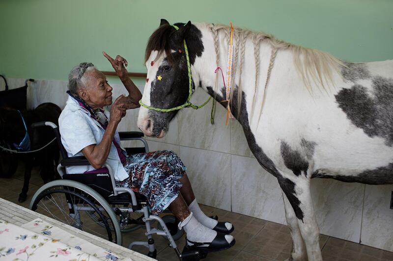 A woman speaks affectionately to a horse named "Tony" at the Maria Vieira Bazani nursing home in Rio de Janeiro, Brazil, on October 22, 2020.  AP Photo