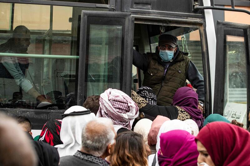 A bus driver wearing a mask as a means of protection against the cononavirus Covid-19, speaks to passengers in the northeastern Syrian Kurdish-majority city of Qamishli.   AFP