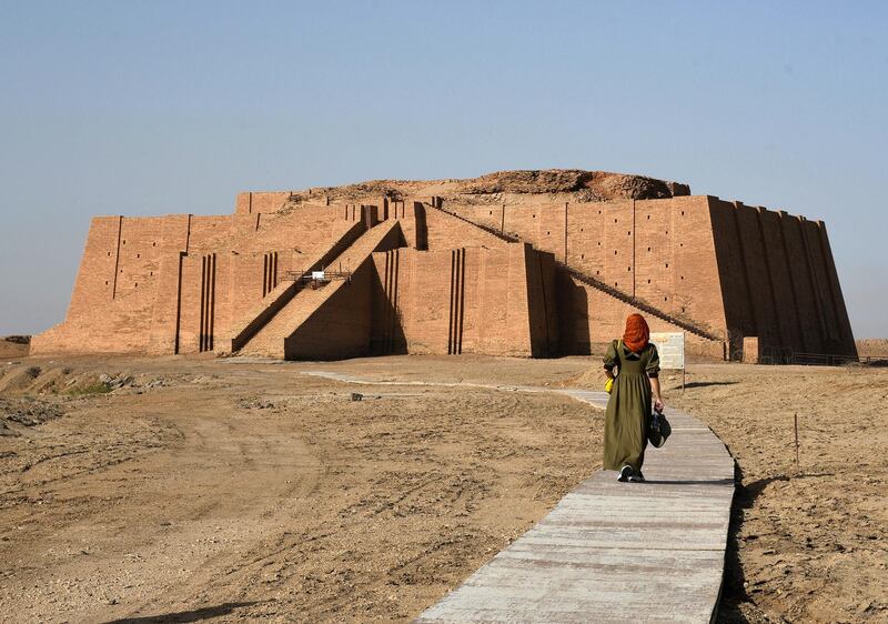 An Iraqi woman walks on June 15, 2020 towards the Great Ziggurat temple, a massive Sumerian stepped mudbrick construction dedicated to the moon god Nanna which dates back to 2100 BC in the ancient city of Ur that falls now in southern Iraq's Dhi Qar province, 375 kilometers (235 miles) southeast of Baghdad. - The location of the city of Ur, where the Bible says Abraham was born, is one of Iraq's oldest archaeological sites of the ancient region of Mesopotamia. (Photo by Asaad NIAZI / AFP)