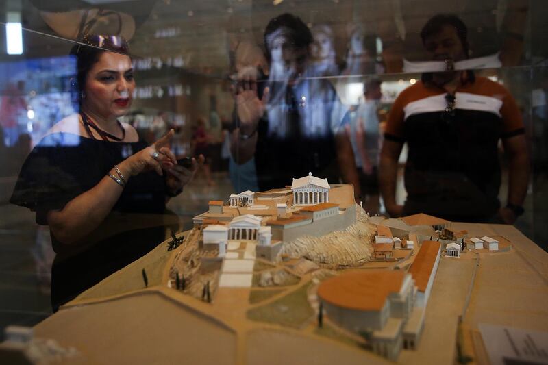 Tourists look at a maquette of the Acropolis Hill as they visit the Museum of Acropolis in Athens, Greece, in June 2019, during the museum's 10 years celebration.  EPA