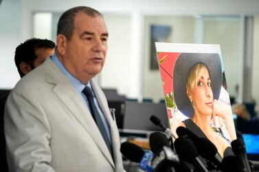 A portrait of late cinematographer Halyna Hutchins, right, is displayed as Brian Panish, an attorney for the family of Hutchins, speaks during a news conference, Tuesday, Feb.  15, 2022, in Los Angeles.  The family of Hutchins is suing Alec Baldwin and the movie producers of "Rust" for wrongful death, the attorneys said Tuesday.  (AP Photo / Chris Pizzello)