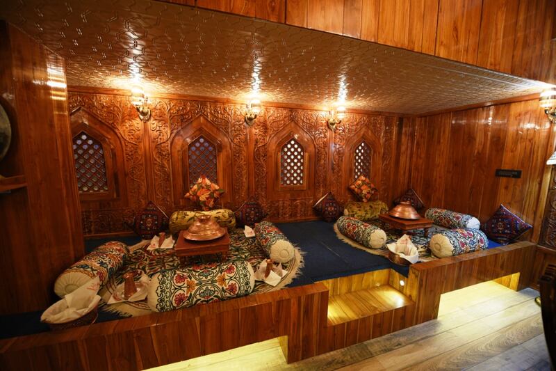 Diners sit crossed-legged on the carpet while being served by staff in traditional Kashmiri attire. Photo: Zarpar