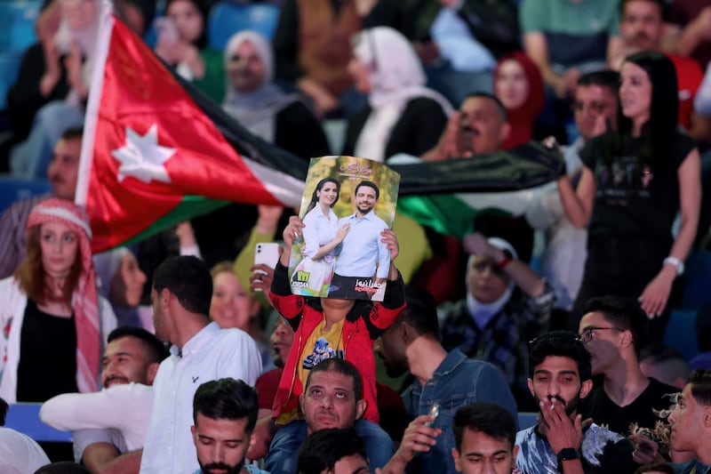 A man holds up a pre-wedding poster showing Jordan's Crown Prince Hussein and his fiance Rajwa Al Saif