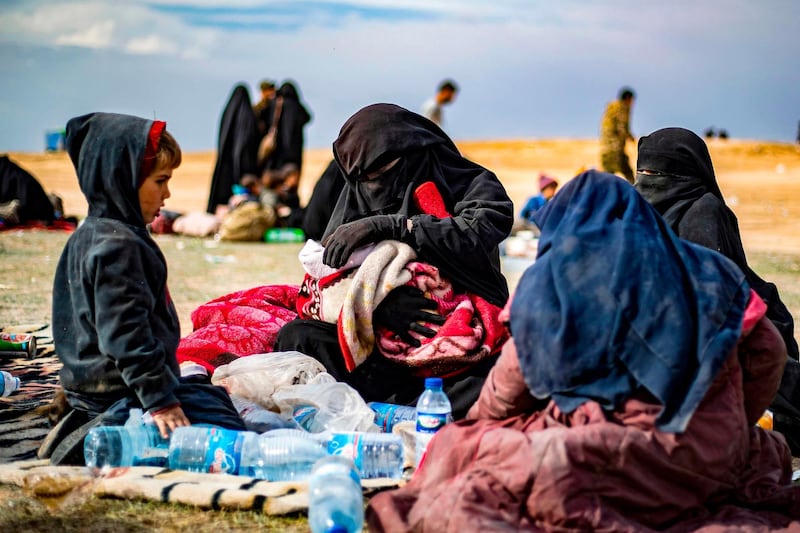 Dorothee Maquere, wife of French jihadist Jean-Michel Clain, sits with four of her five children at a screening area in the eastern Syrian province of Deir Ezzor, after fleeing the Islamic State (IS) group's embattled holdout of Baghouz, on March 5, 2019, during an operation by US-backed Syrian forces to expel IS jihadist from the area. Maquere told AFP that her husband was killed last month two days after a coalition strike killed his brother Fabien. While Fabien was seen as a senior propagandist among the foreign fighters ranks of IS, his younger brother was known as a singer of the "nasheed" chants heard on some of the videos released by the organisation. / AFP / Delil SOULEIMAN
