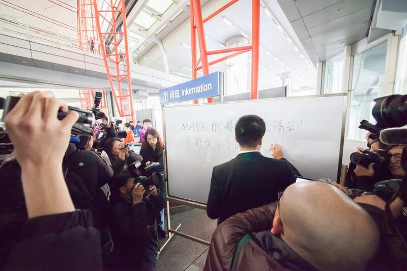 An airport representative writes a notice aimed at relatives of passengers onboard Malaysia Airlines Flight MH370 to gather at the local Holiday Inn at Beijing International Airport. Getty