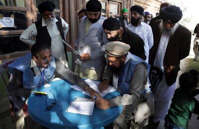 Men from the minority Sikh register to cast their votes in Parliamentary elections in old city of Kabul, Afghanistan, Saturday, Oct. 20, 2018. Tens of thousands of Afghan forces fanned out across the country as voting began Saturday in the elections that followed a campaign marred by relentless violence. (AP Photo/Massoud Hossaini)
