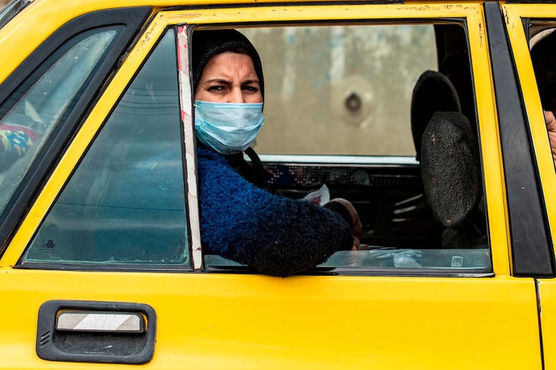 A woman wearing a mask as a means of protection against the cononavirus Covid-19, gazes out of a car window in the northeastern Syrian Kurdish-majority city of Qamishli.   AFP