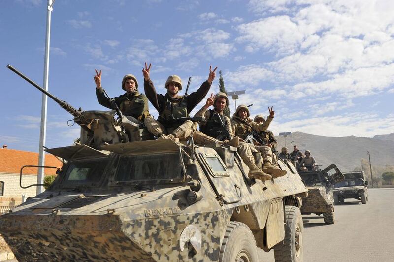 Lebanese soldiers gesture while riding on an armoured vehicle as they leave the mountainous border town of Ras Baalbek. Reuters