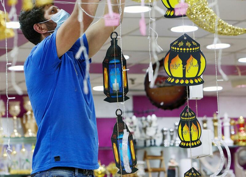 A vendor decorates his shop with lanterns, at a market in Kuwait City, the day before the start of the holy month. AFP