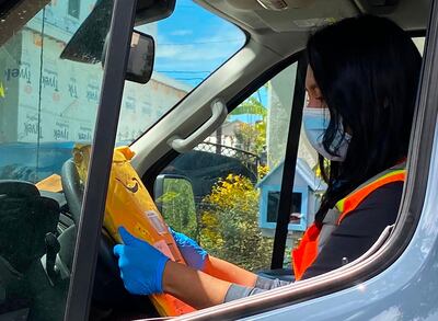 (FILES) In this file photo taken on April 08, 2020, Angela, a delivery worker for Amazon Prime, wears a mask and gloves on her route in Los Angeles. Amazon is moving to create it own lab to test employees for coronavirus as the e-commerce giant struggles with safety issues amid the pandemic. "A team of Amazonians with a variety of skills -- from research scientists and program managers to procurement specialists and software engineers -- have moved from their normal day jobs onto a dedicated team to work on this initiative," the company said in a blog post late April 9, 2020. / AFP / Chris DELMAS
