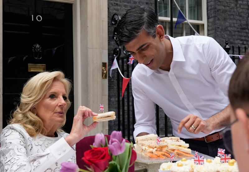 Mr Sunak holds a plate of sandwiches for US First Lady Jill Biden at Downing Street to celebrate King Charles' coronation. Getty Images