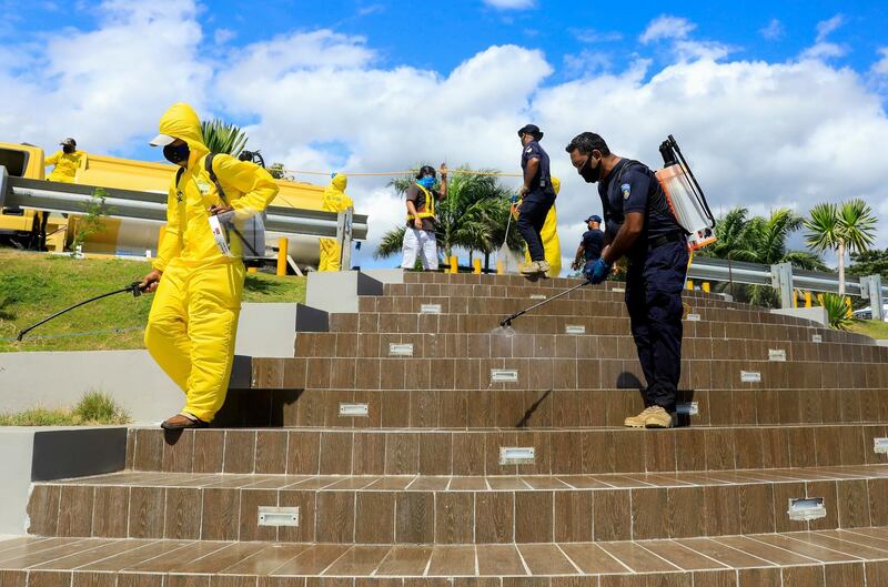 Health workers and police officers spray disinfectant on a city park in Dili, Timor Leste. EPA