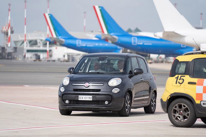 Pope Francis, left, arrives in a car at the airport in Rome, for his flight to Marseille. EPA