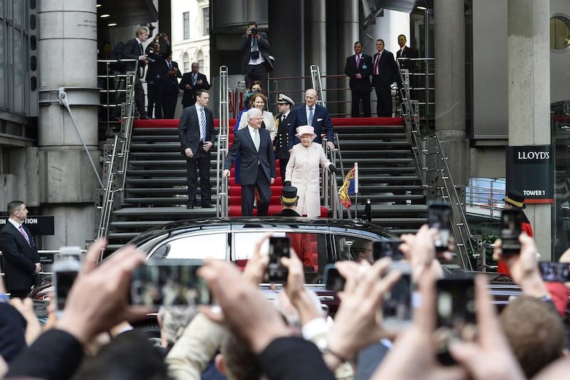 Queen Elizabeth II, centre, and Prince Philip, the Duke of Edinburgh centre right, are greeted by members of the public after visiting Lloyd’s of London recently. Facundo Arrizabalaga / EPA