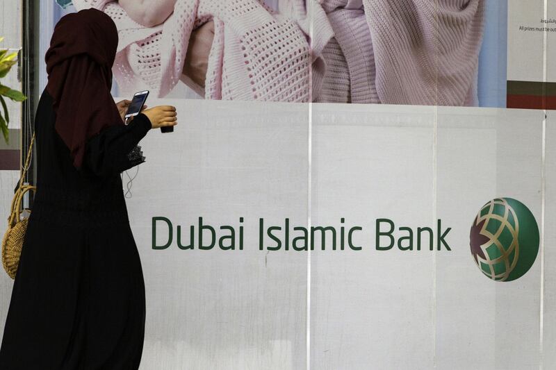 A pedestrian checks her smartphone while passing a Dubai Islamic Bank PJSC bank branch in Dubai, United Arab Emirates, on Tuesday, Sept. 4, 2018. Abu Dhabi is engineering a second bank merger in its latest attempt to stay competitive in the era of lower oil prices. Photographer: Christopher Pike/Bloomberg