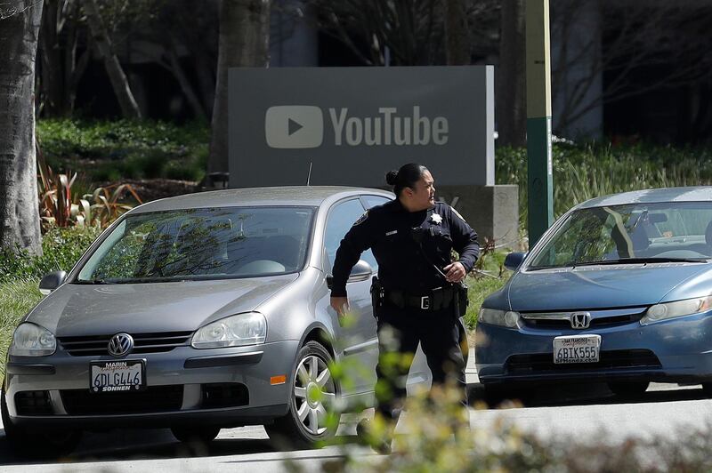 An officer runs past a YouTube sign near the company's complex in San Bruno. Four people were wounded before the shooter killed herself, police and witnesses said. AP Photo/Jeff Chiu