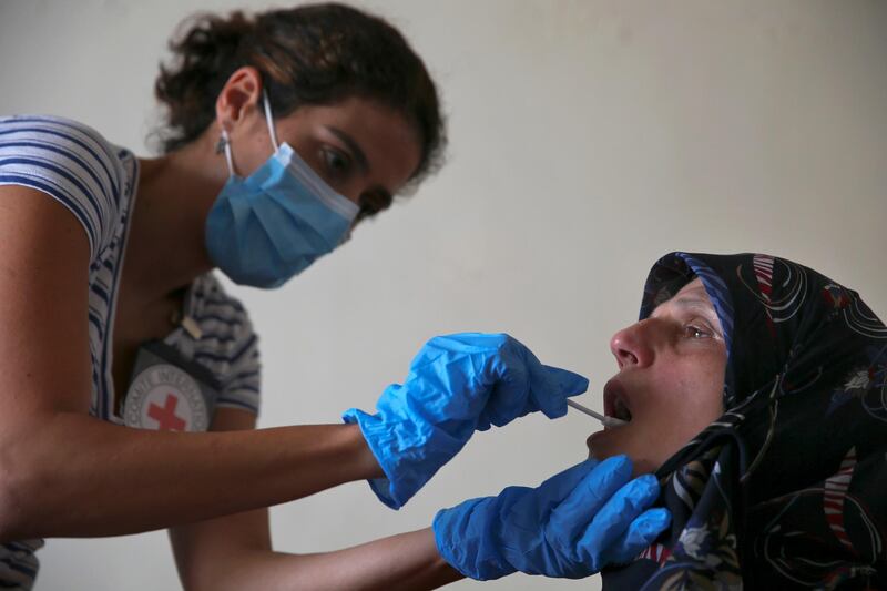 FILE - This Monday, July 11, 2016 file photo, a member of The International Red Cross takes a saliva sample from Umalbaneen Ali Wehbe, sister of Habib Ali Wehbe who went missing in 1976 during the Lebanese civil war, at her home, in the southern suburb of Beirut Beirut, Lebanon. Lebanon's parliament approved Monday, Nov. 12, 2018 the formation of an independent commission to help determine the fate of thousands of people who went missing during the country's civil war 28 years after it ended. (AP Photo/Hassan Ammar, File)