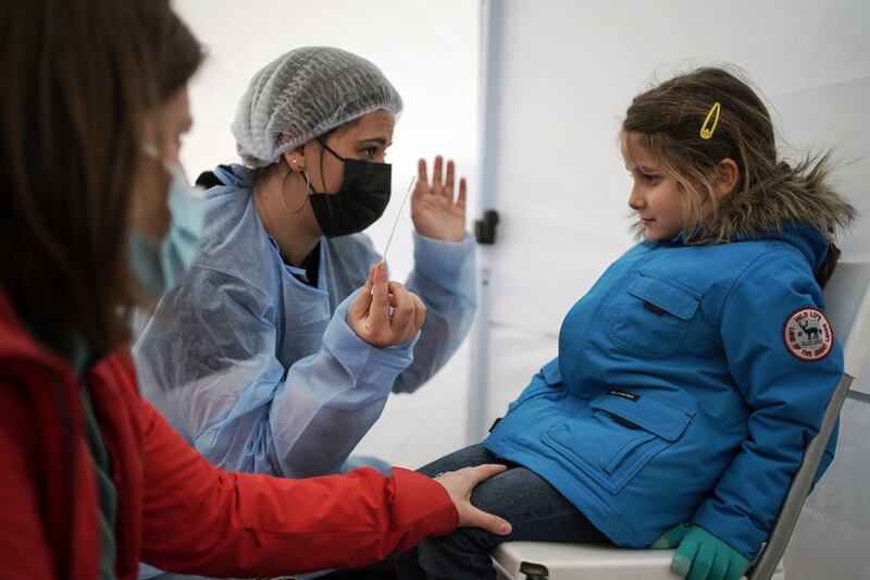 A health worker explains to a young child how she will get a nasal swab at a mobile Covid-19 testing site in Albigny-sur-Saone, outside Lyon, central France. AP