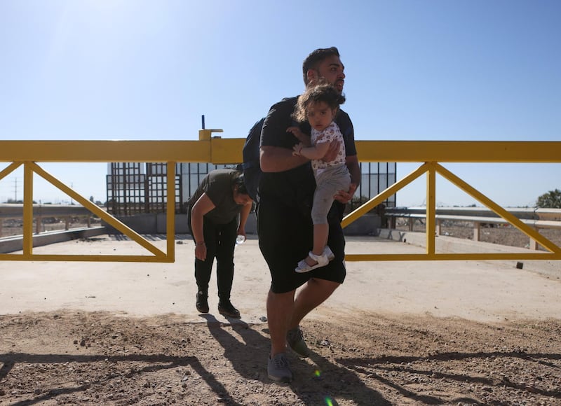 A couple from Romania crosses into the United States, as the man carries his daughter, in San Luis, Arizona, U.S., April 19, 2021. REUTERS/Jim Urquhart REFILE - ADDITIONAL CAPTION INFORMATION