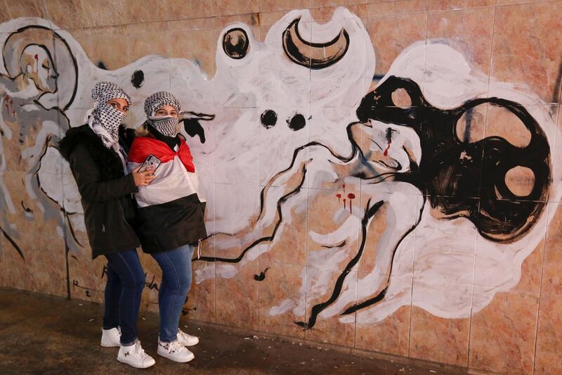 Iraqi protesters pose for a picture next to a mural in Tahrir square in the capital Baghdad. EPA